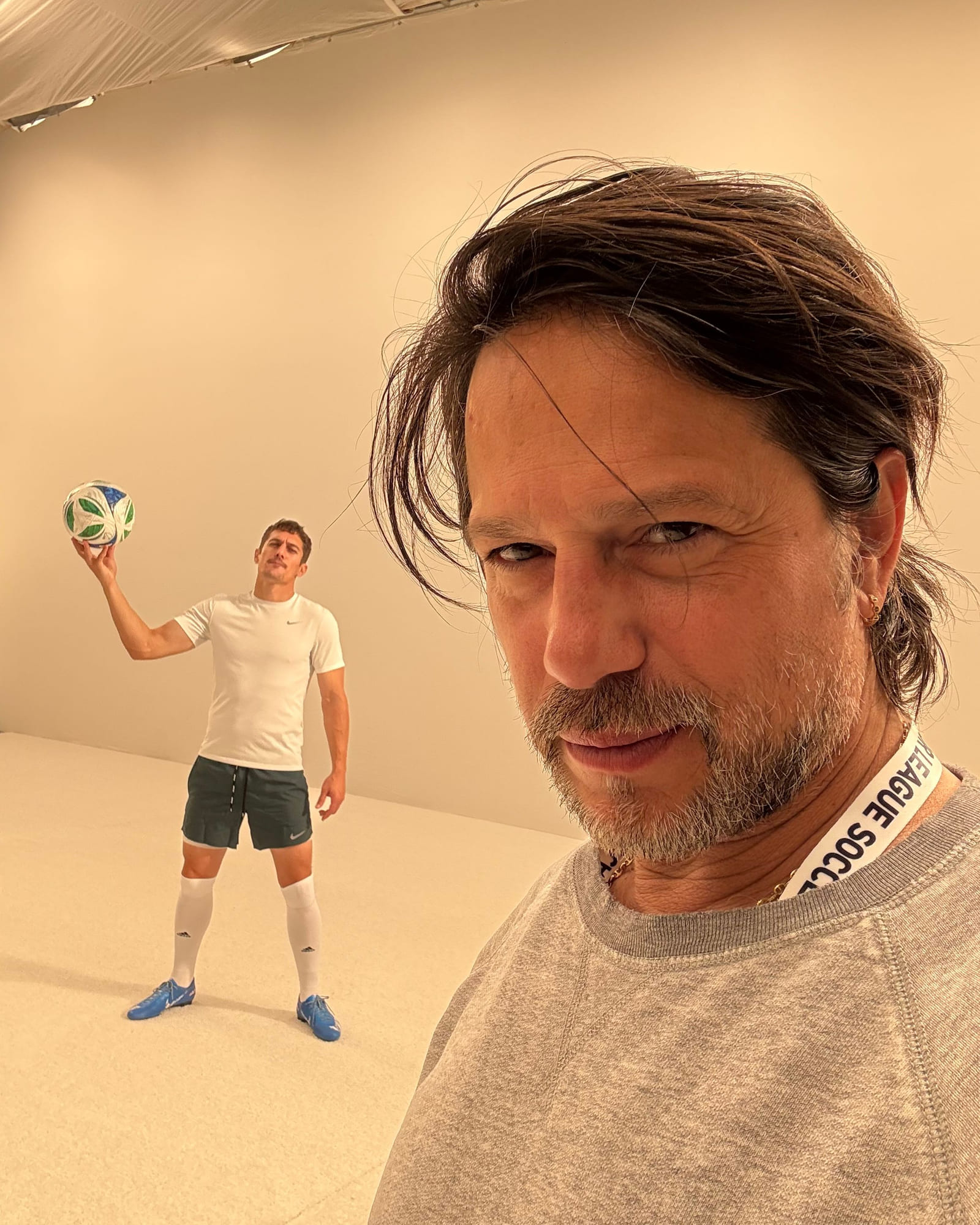 A crew member's selfie on the Apple set, Bryan Jordan behind him on the white cyclorama in a Nike kit, holding a football up in one hand.